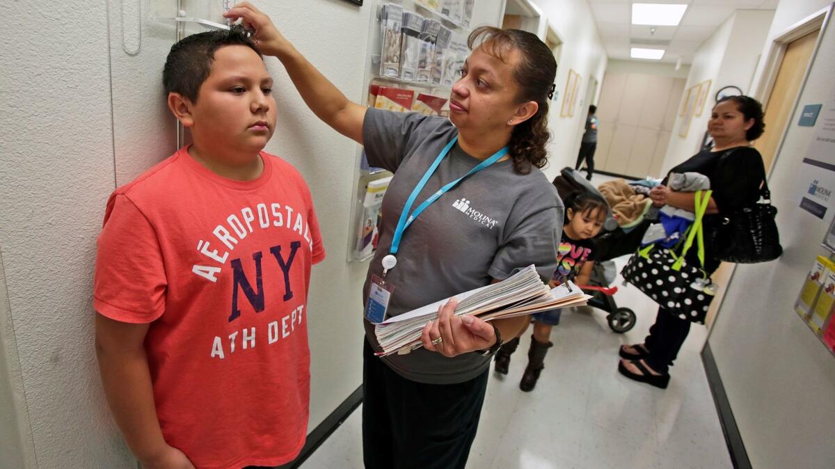 Nurse Marisol Vasquez measures the height of Victor Garcia who was at Molina Health Clinic in 2013 with his mother Marisela Garcia, right, and siblings.