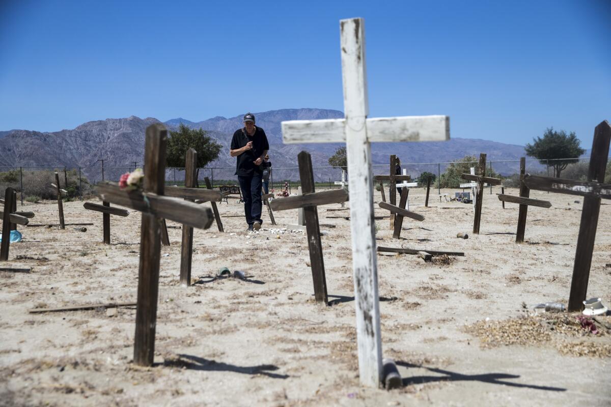 Photographer Doug McCulloh walks among wooden crosses at the Sacred Hearts of Jesus and Mary Catholic Cemetery at the Torres Martinez Indian Reservation in Thermal, Calif.
