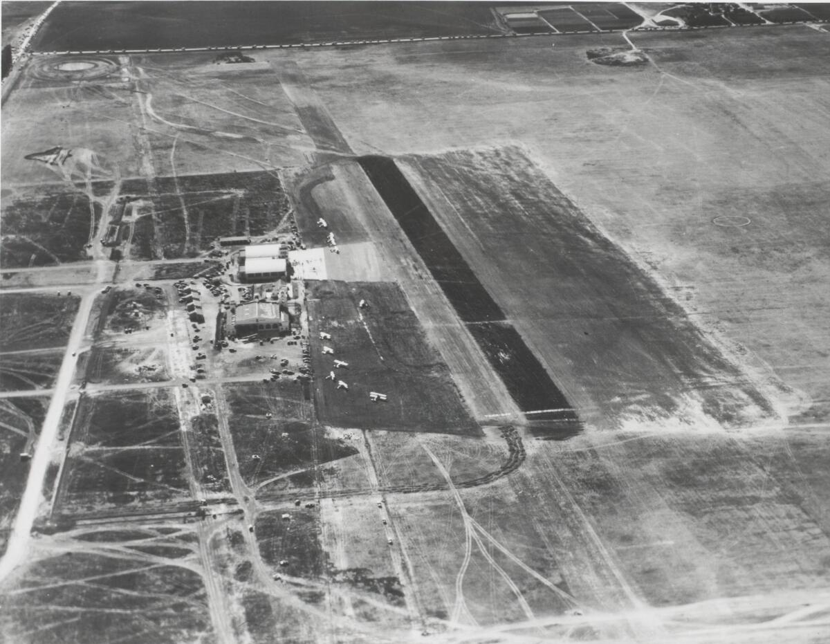 A black-and-white aerial view of a small airport surrounded by fields