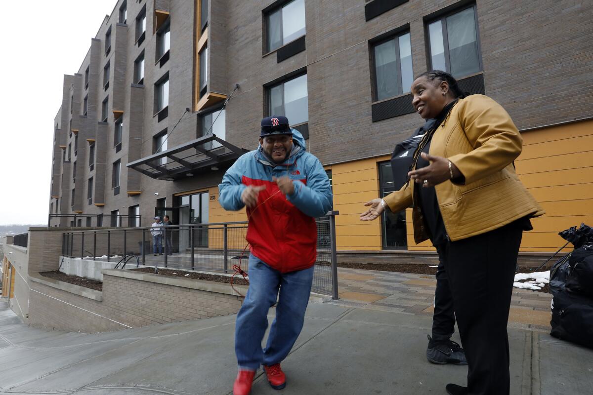 Jesus Melendez, 46, left, rushed to move his belongings into his studio apartment at Landing Road, a new shelter and long-term housing facility in the Bronx, where Marguerite Brown welcomes him and other new residents.
