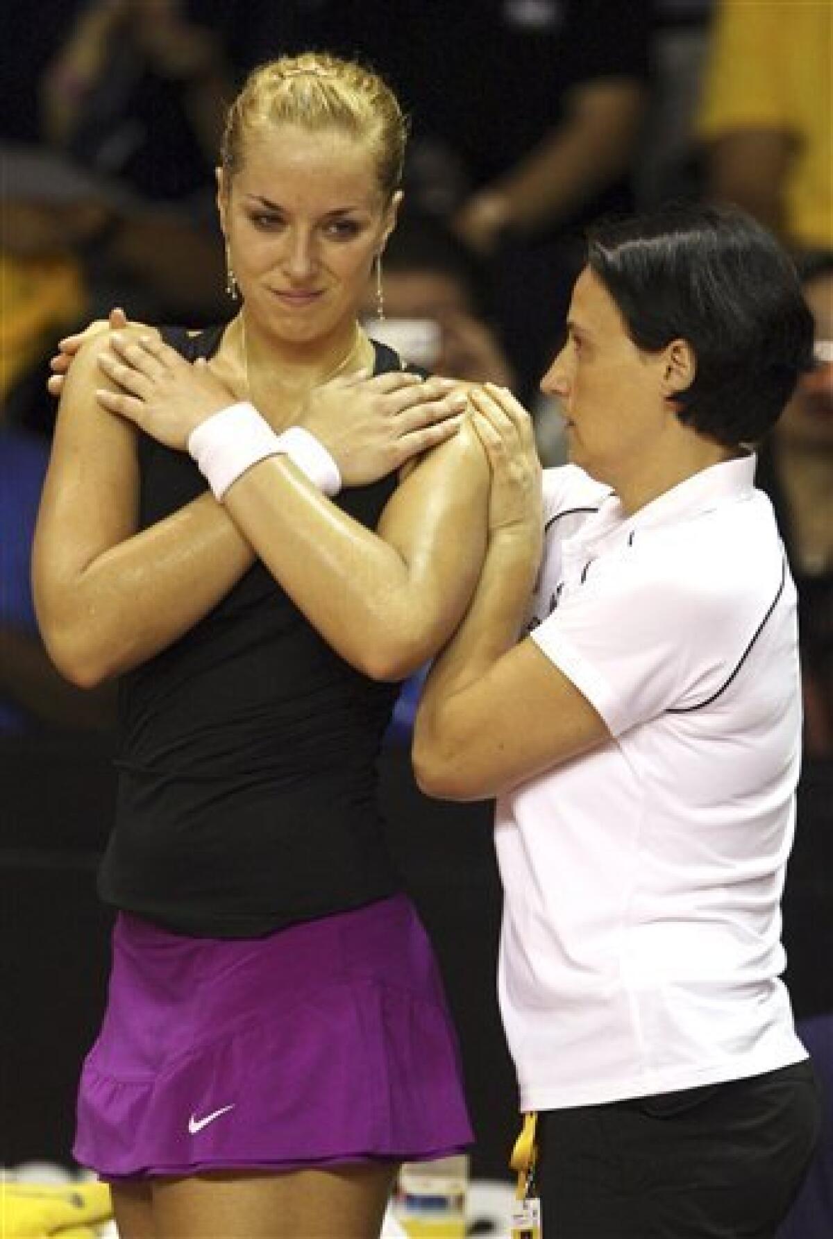 Sabine Lisicki of Germany, left, has treatment during her semifinal tennis match against Anabel Medina Garrigues of Spain at the Bali Tournament of Champions in Nusa Dua, Bali, Indonesia, Saturday, Nov. 5, 2011. Garrigues won the match as Lisicky retired with a back injury. (AP Photo/Firdia Lisnawati)