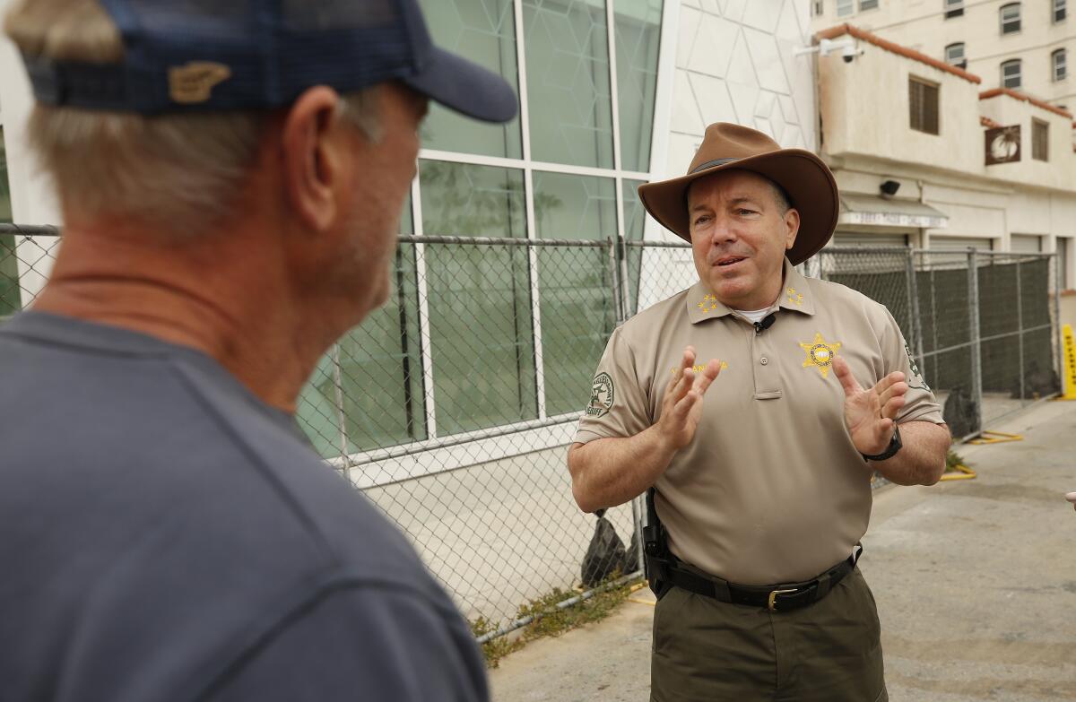 Sheriff Alex Villanueva, wearing a cowboy hat, talks to a business owner