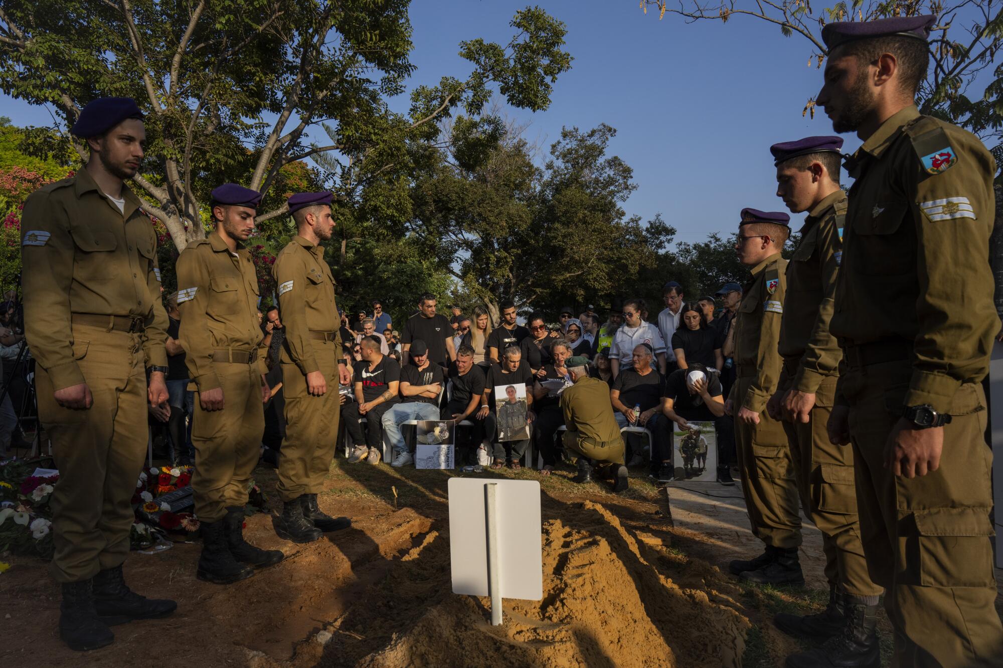Israeli soldiers standing next to the grave of a fallen comrade