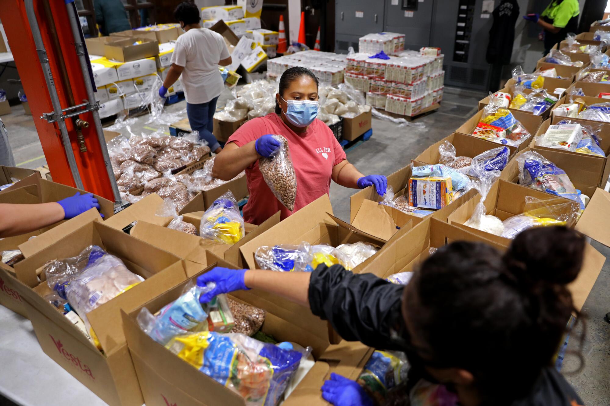 La voluntaria Margarita González prepara cajas de comida para ser distribuidas a unas 1.800 familias por el Mission Food Hub.