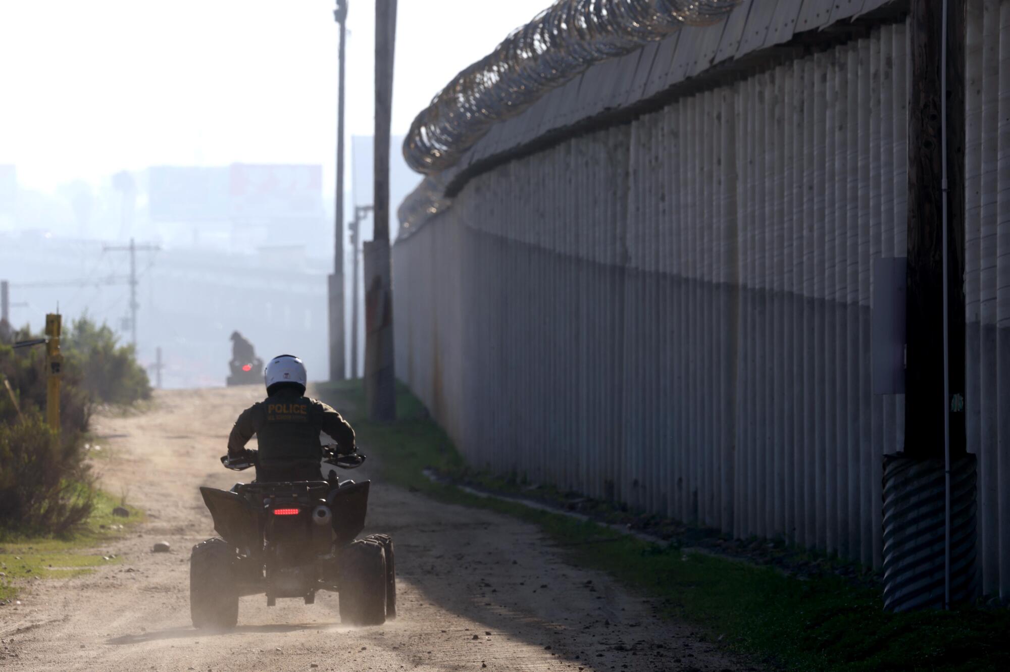 Construction workers in Tijuana work on the road above the border walls of the United States and Mexico.