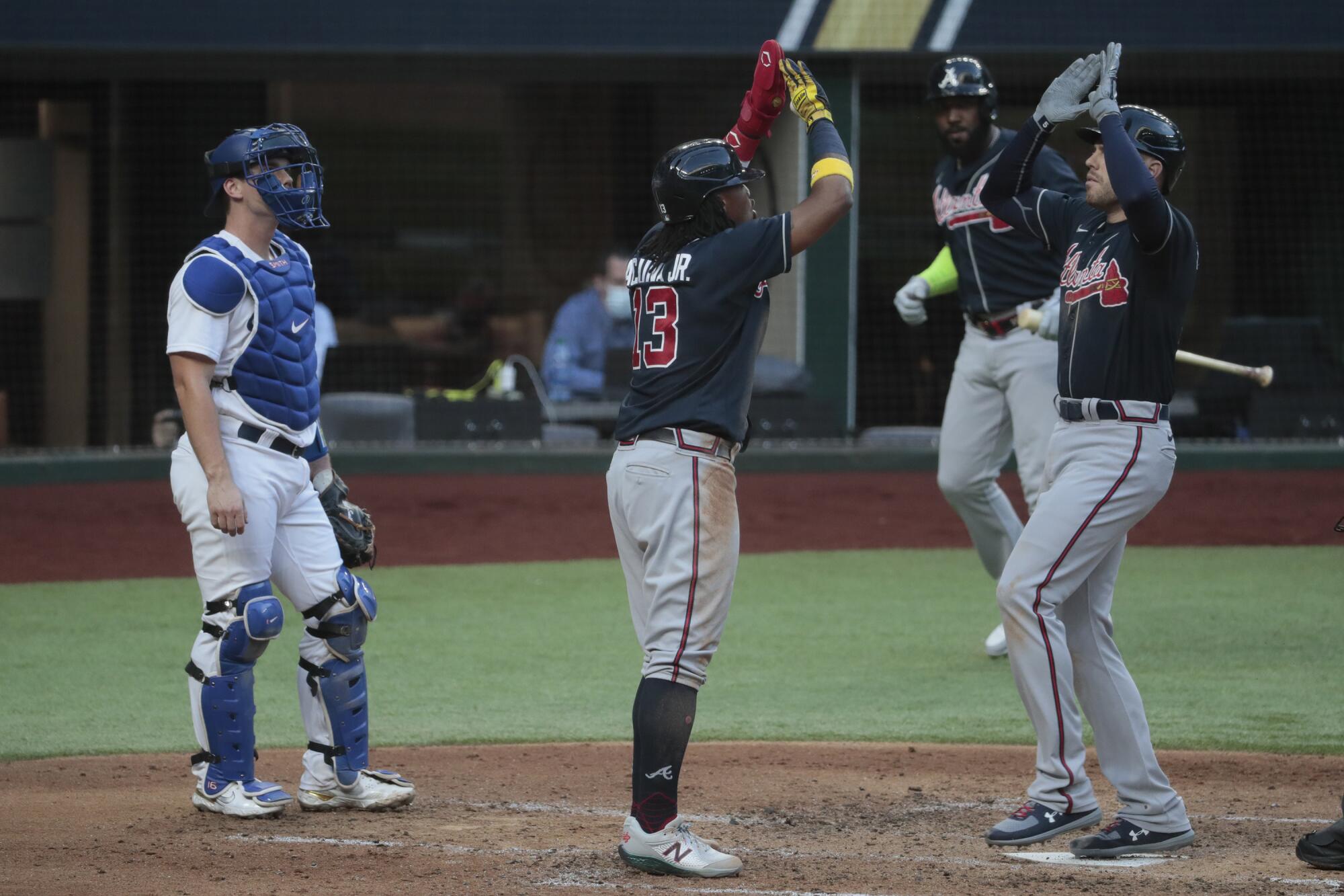 Atlanta's Freddie Freeman, right, celebrates with Ronald Acuna Jr. in front of Dodgers catcher Will Smith.