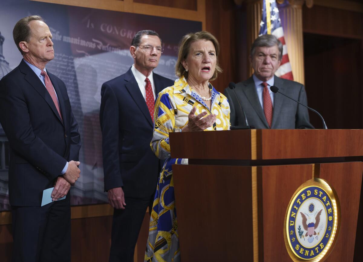 Sen. Shelley Moore Capito, joined by three fellow senators, speaks from a lectern.