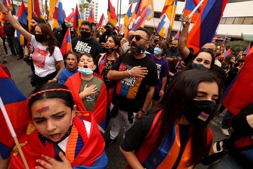 People sing while holding Armenian flags.