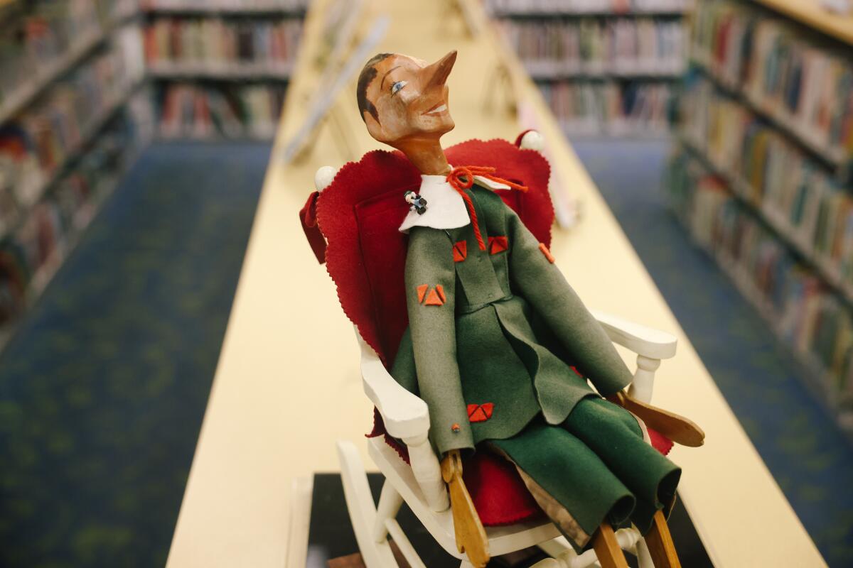 A wooden Pinocchio doll seated in a rocking chair.
