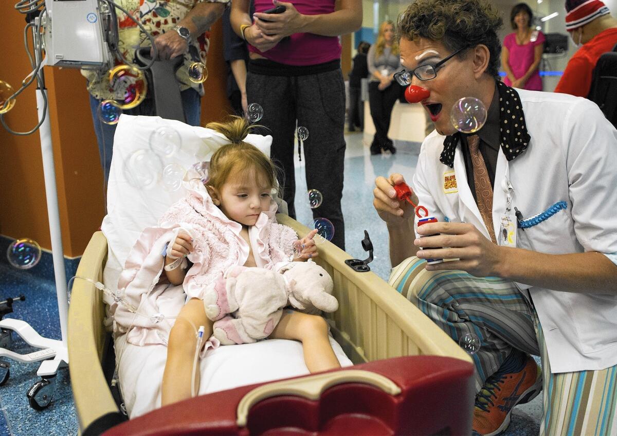Bella Watkings, 2, of Lake Arrowhead is entertained with bubbles by "Doctor Buns," played by Skyler Sullivan during Clown Care at Children's Hospital of Orange County on Thursday.