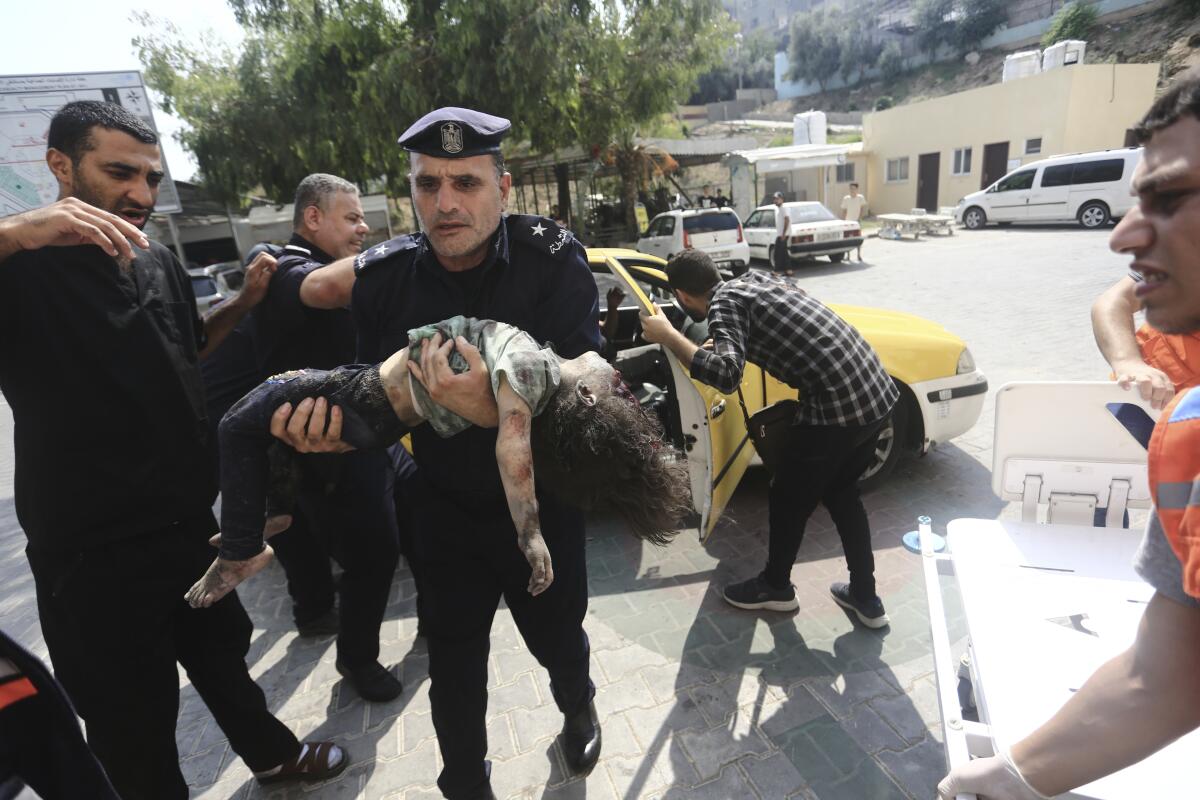 Un polica de Hamas llega con una nia herida a un hospital en Beit Lahiya, en la Franja de Gaza, el domingo 8 de octubre de 2023. (AP Foto/Mahmoud Essa)