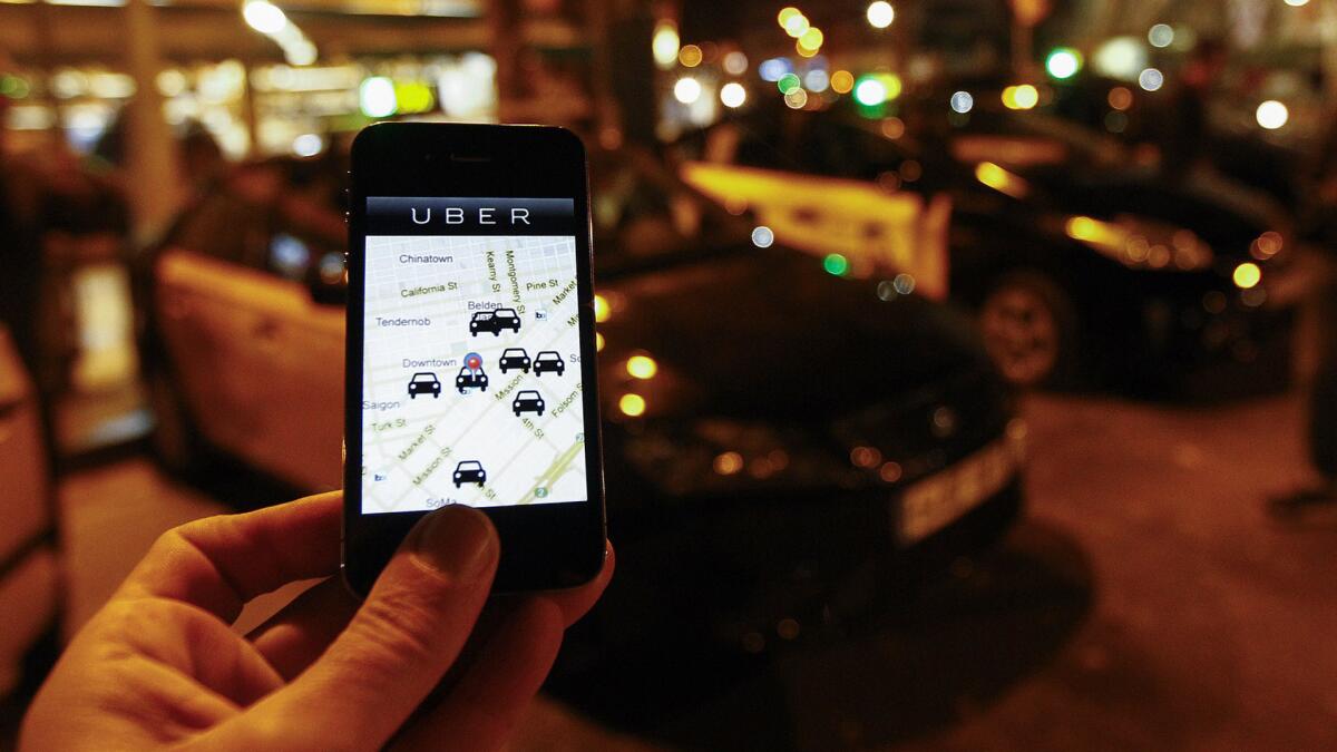 The Uber app is seen on a smartphone past cabs waiting for riders.