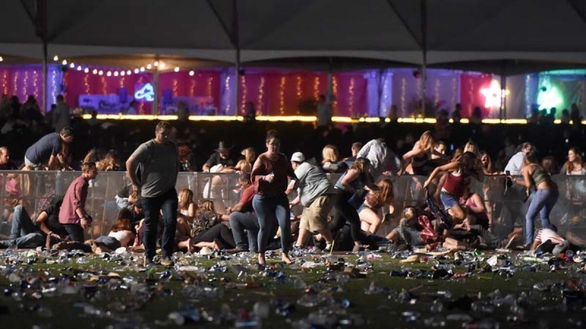 Concert-goers flee as gunfire from across the street hits the Route 91 Harvest festival at Las Vegas Village on Sunday.