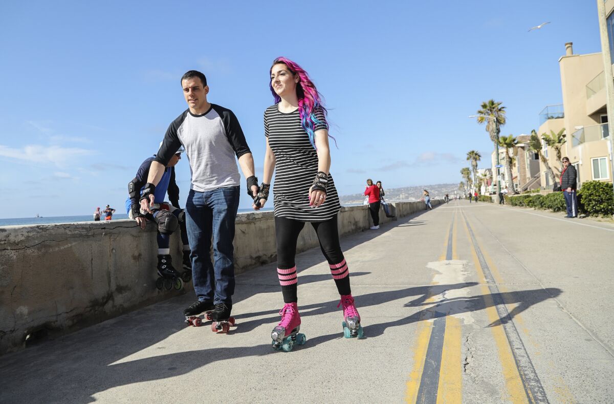 Cody and Monica Manjarrez roller skate along the boardwalk in Mission Beach. The couple lost weight together using the WW (Weight Watchers) program and by exercising together.