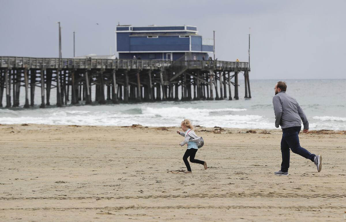 Jim Freeman and daughter Emma run in the cold wind just before the rain begins to fall on Wednesday at the Newport Pier.