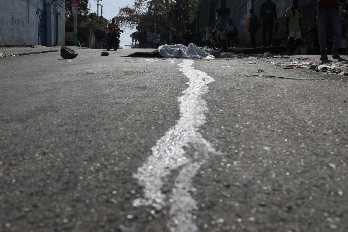 Blood streams from a body lying in the street in the Petion-ville area of Port-au-Prince, Haiti.