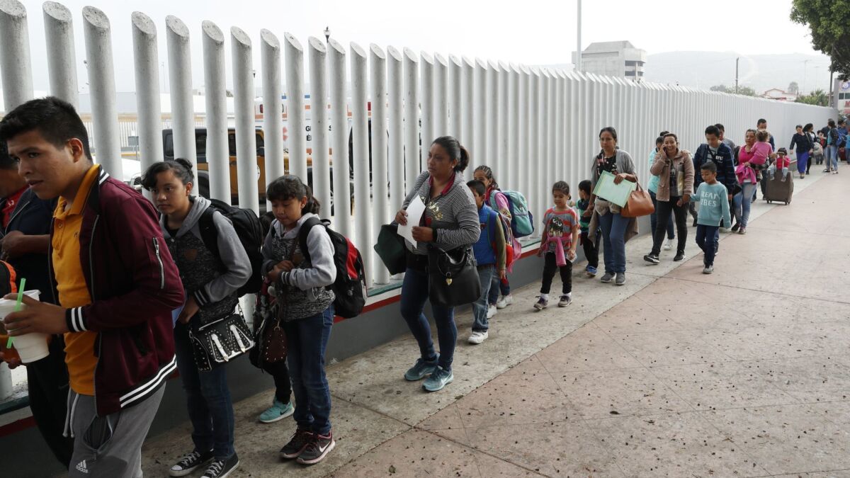 Asylum seekers line up outside the El Chaparral border crossing, as they wait for their numbers to be called so they can be processed, in Tijuana, Baja California State, Mexico.