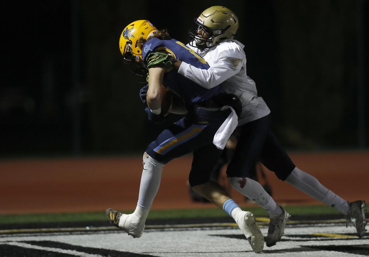 Marina's Dane Brenton, left, scores the game's first touchdown on a 25-yard catch against Muir's Jamier Johnson in the second quarter of the CIF Southern Section Division 11 title game on Friday at Westminster High.
