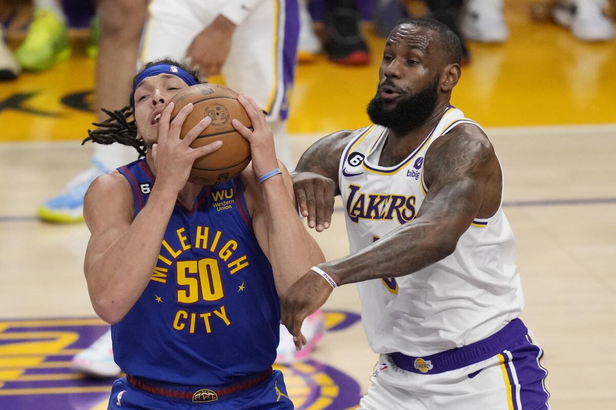 Lakers forward LeBron James, right, defends Nuggets forward Aaron Gordon as he tries to control the ball.