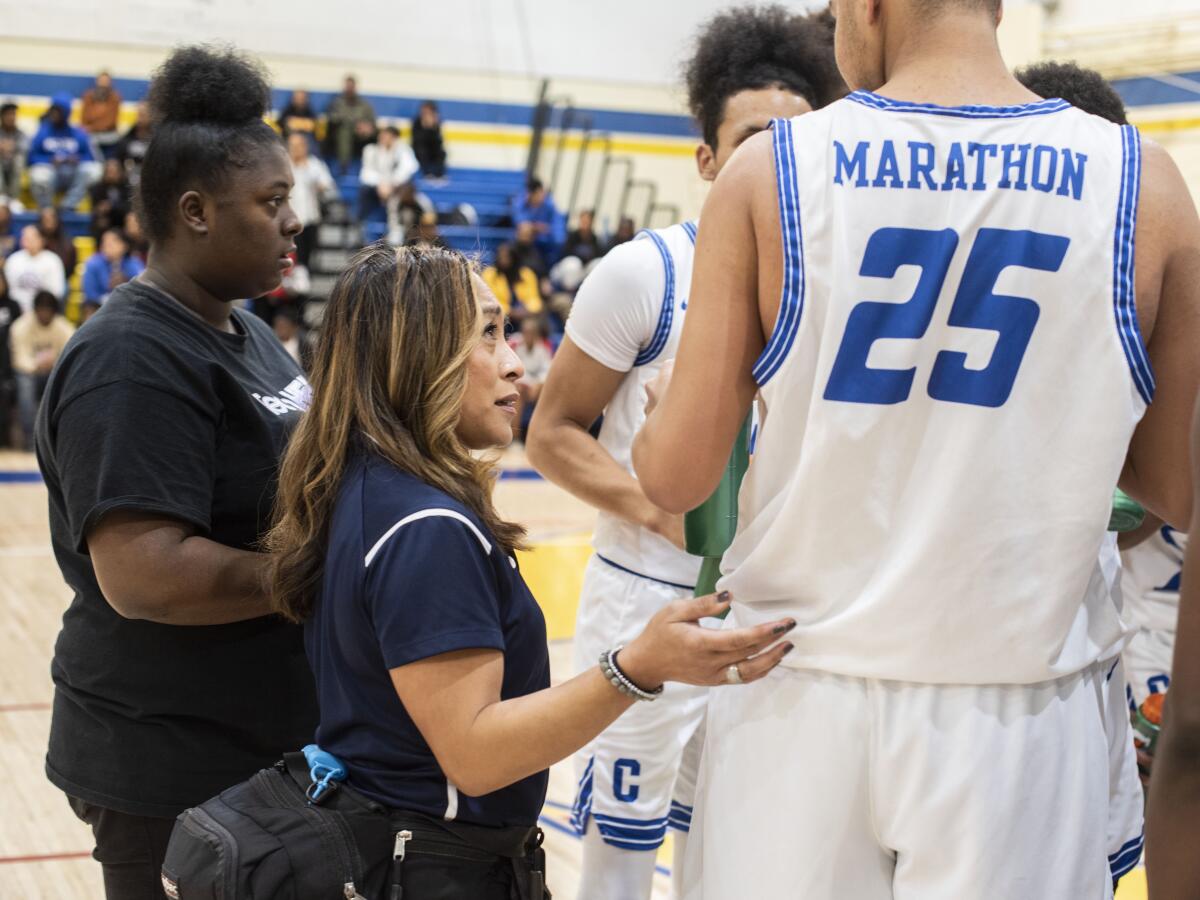 Athletic trainer Ellen Kelly checks in with one of the Crenshaw basketball players during a game Jan. 24, 2020.