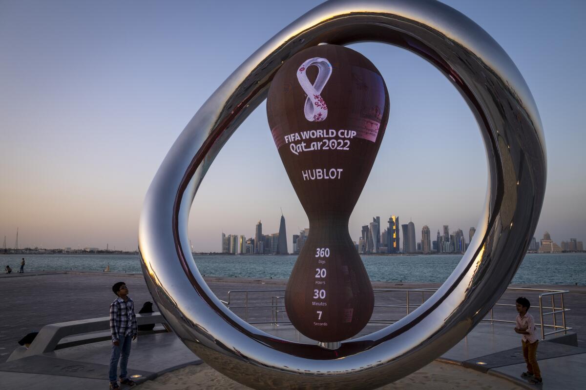 Children stand next to the official countdown clock showing remaining time until the World Cup 2022 in Doha, Qatar.