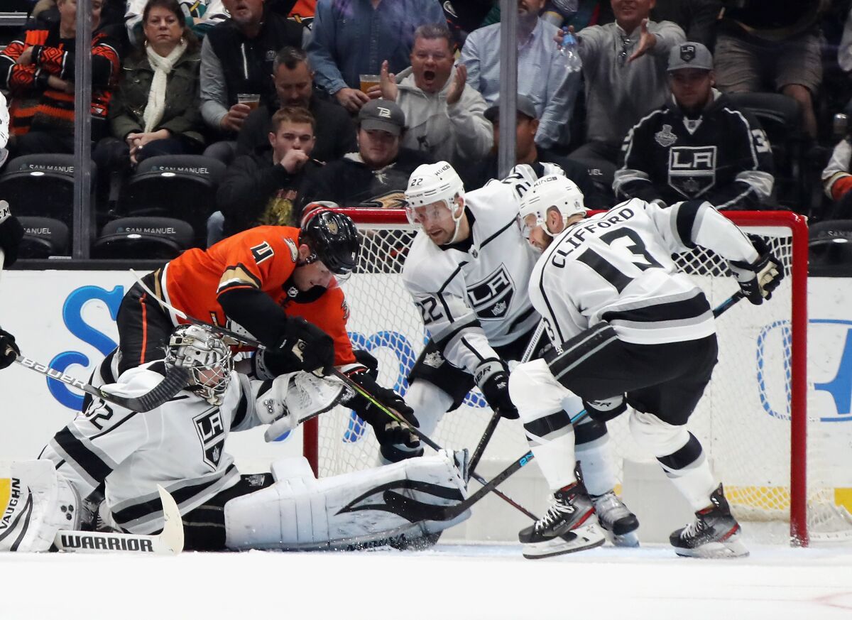 Kings goaltender Jonathan Quick and teammates Trevor Lewis and Kyle Clifford try to stop Ducks defenseman Cam Fowler from scoring.