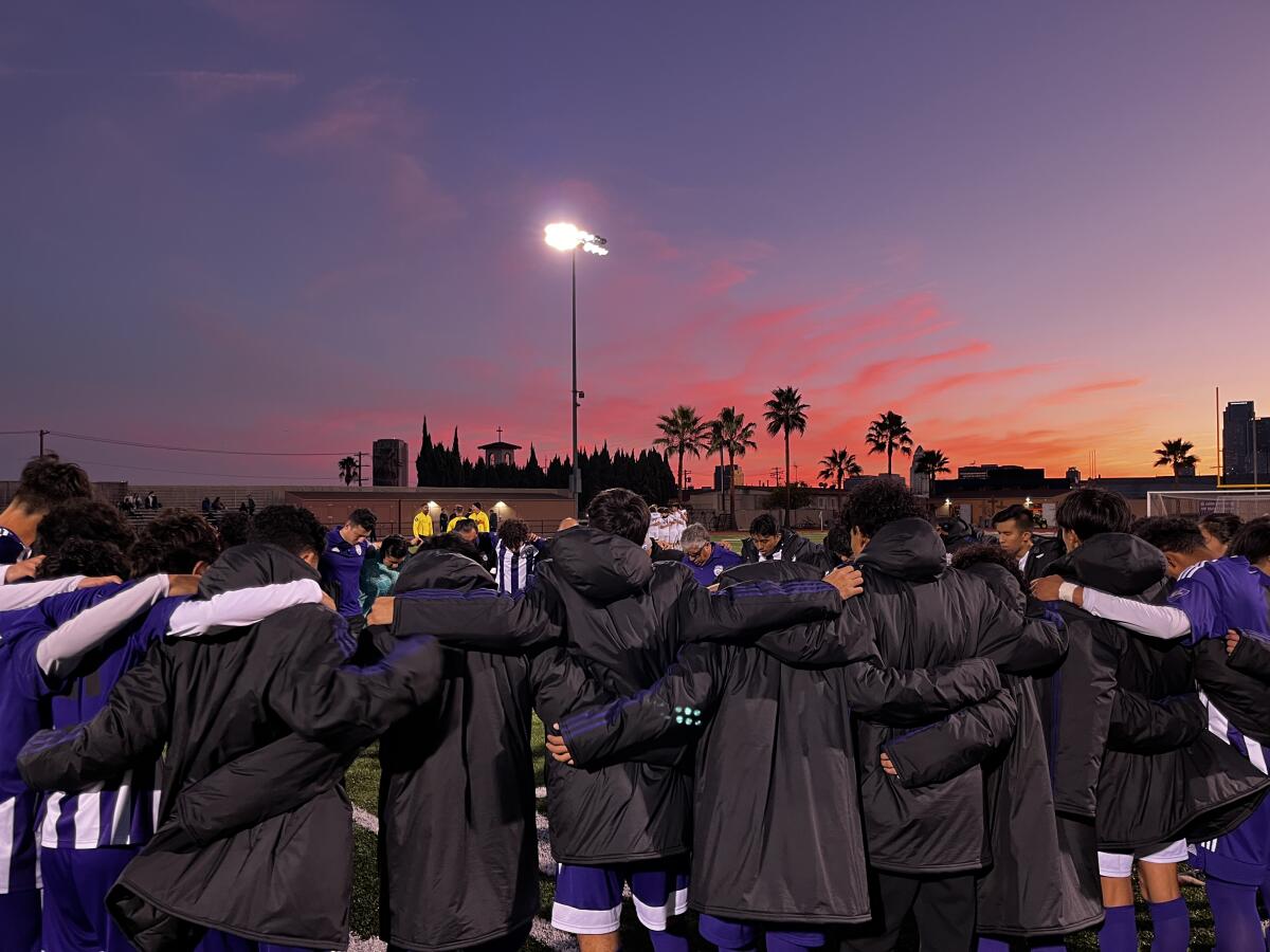 Cathedral High players bow their heads for prayer before Saturday night's rivalry soccer match against Loyola.