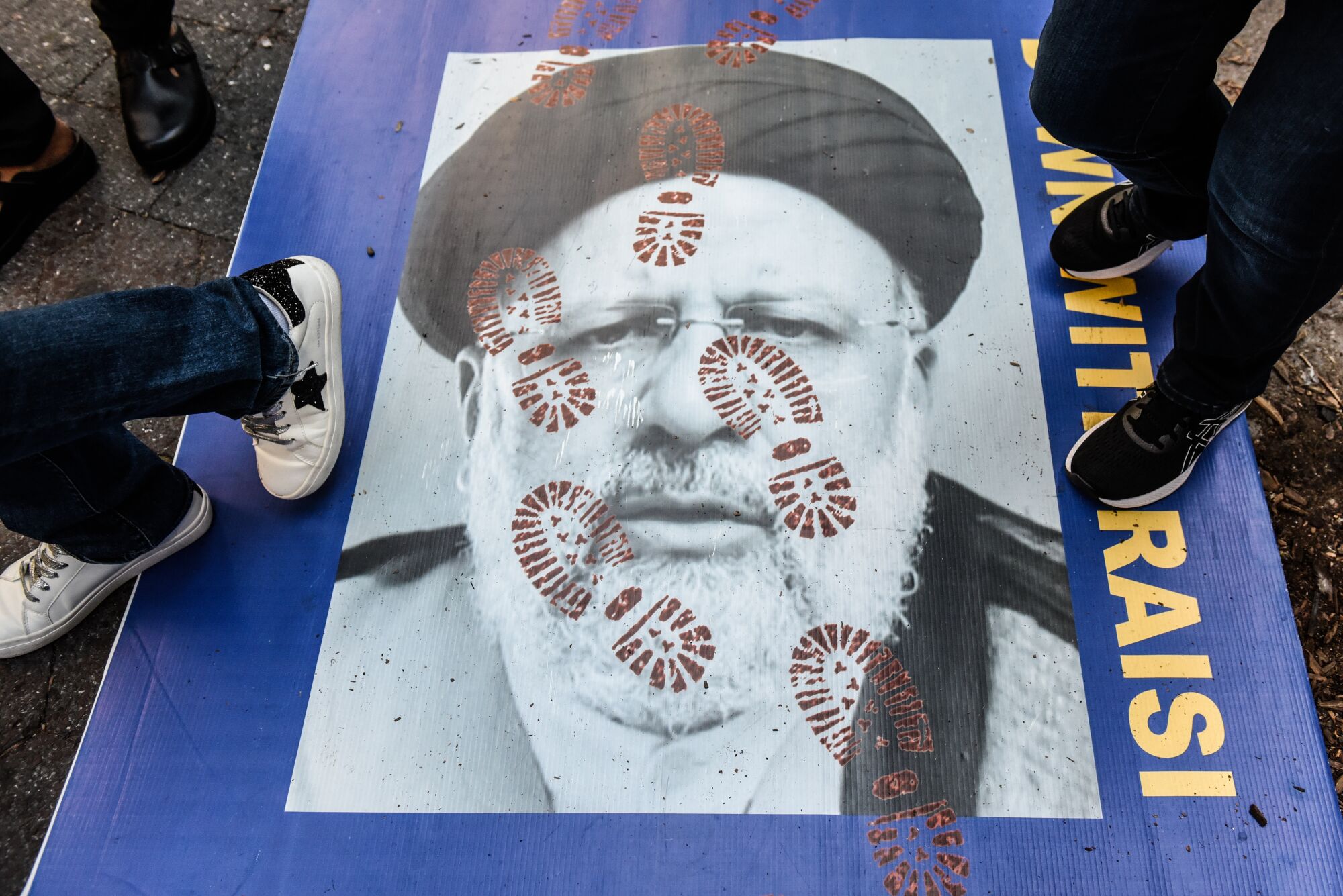 People step on a poster of Iranian President Ebrahim Raisi 