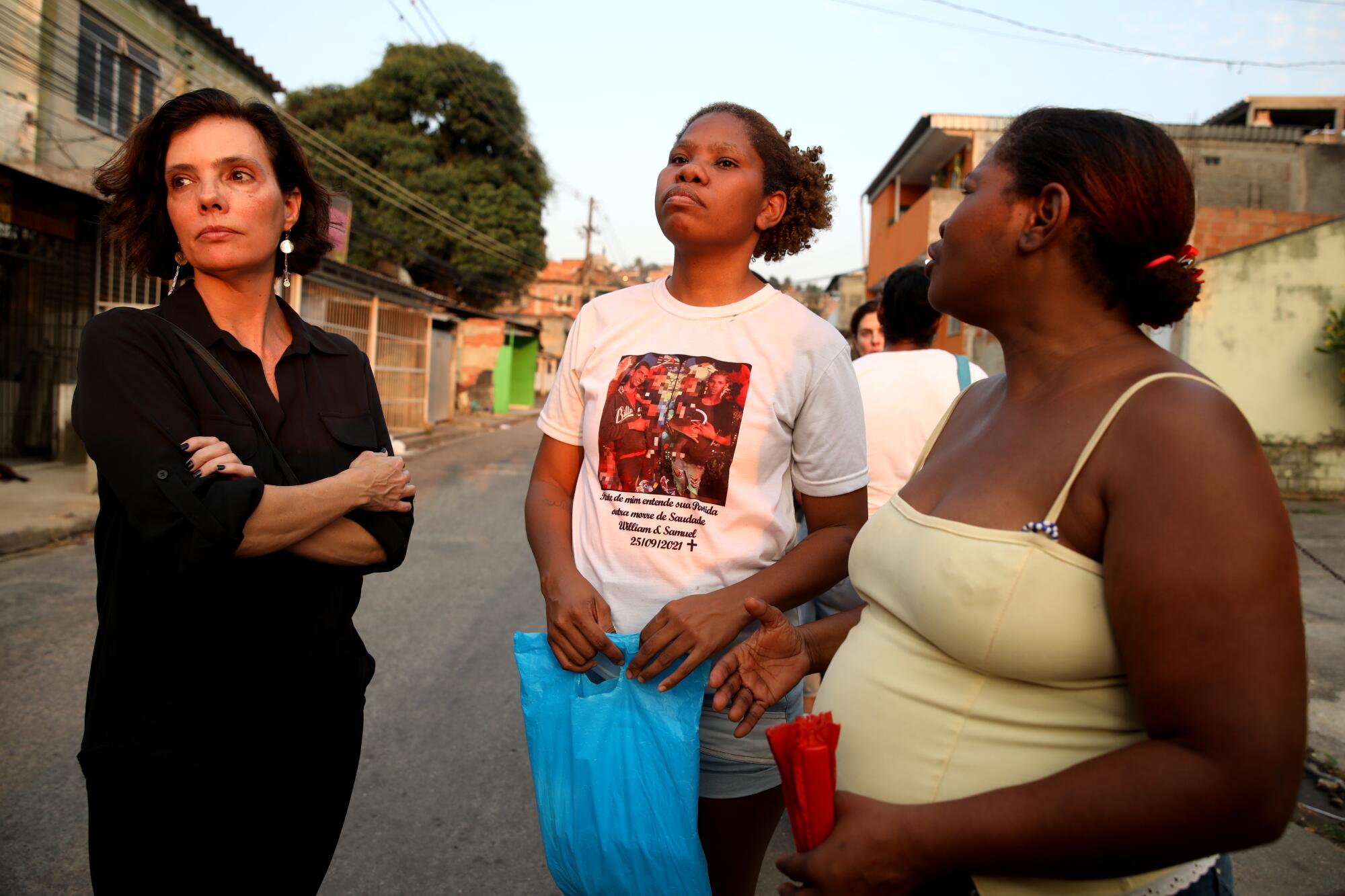 Three women stand in a street.