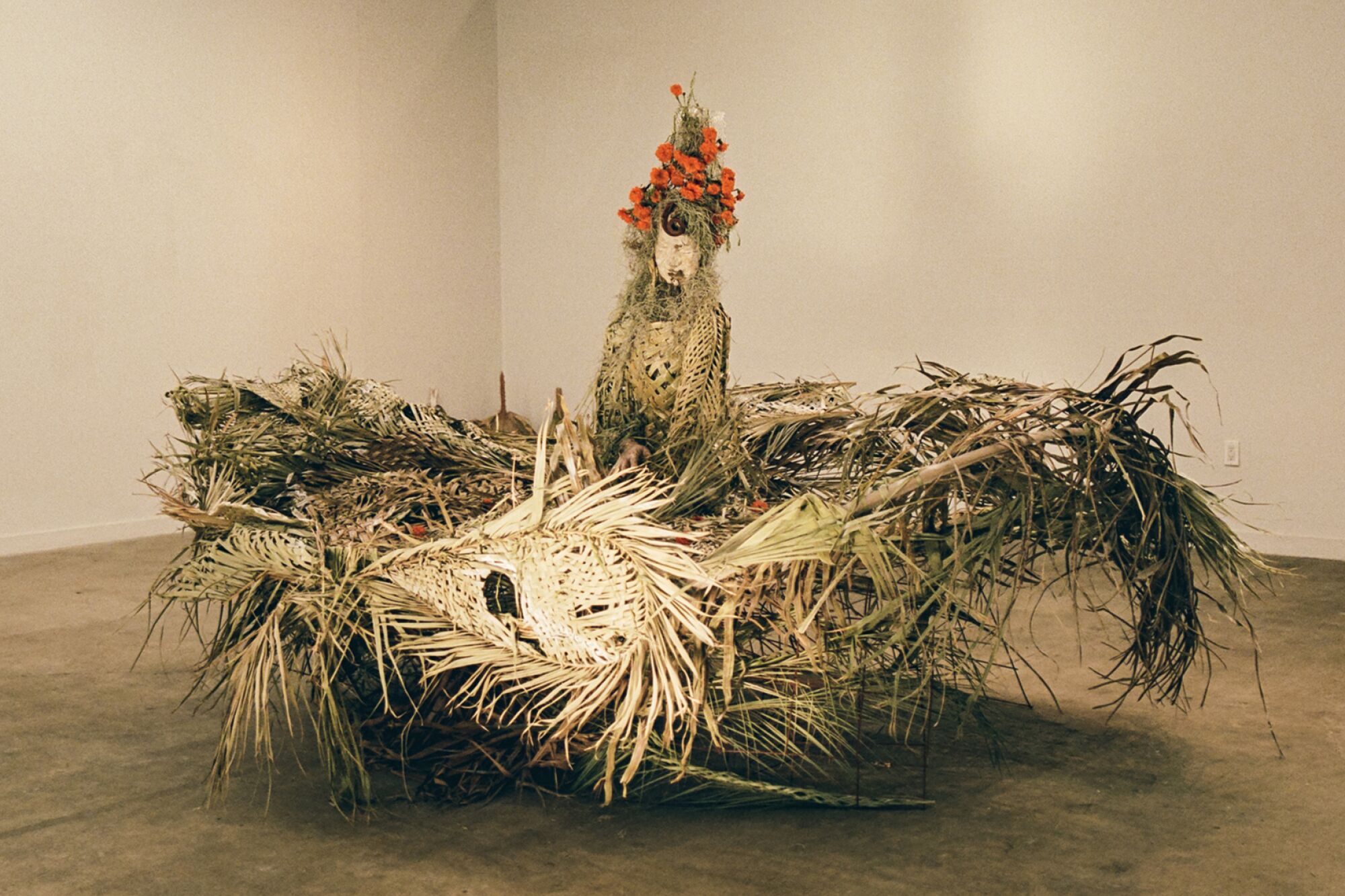 Un tourbillon de feuilles de palmier se dresse au centre de la galerie Murmurs, tandis qu'émerge une sculpture de la mère de Maria Maea.