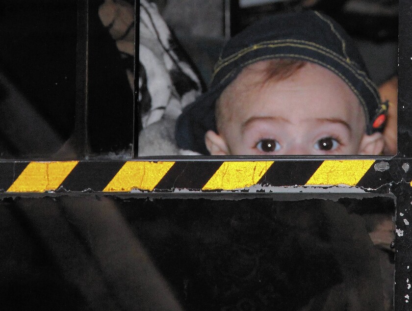 A Syrian child peers from a bus as United Nations workers evacuate people from Homs, Syria.