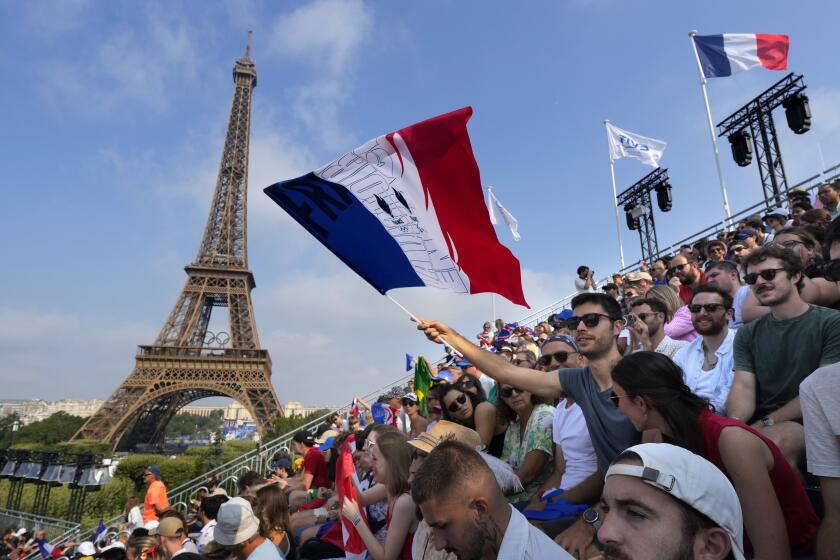 A spectator waves a French flag during a beach volleyball match at the 2024 Summer Olympics, Friday, Aug. 2, 2024, in Paris, France. (AP Photo/Robert F. Bukaty)