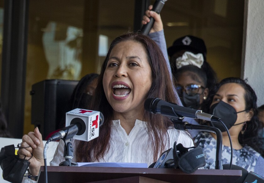 Aurea Montes-Rodriguez speaks into microphones at a podium