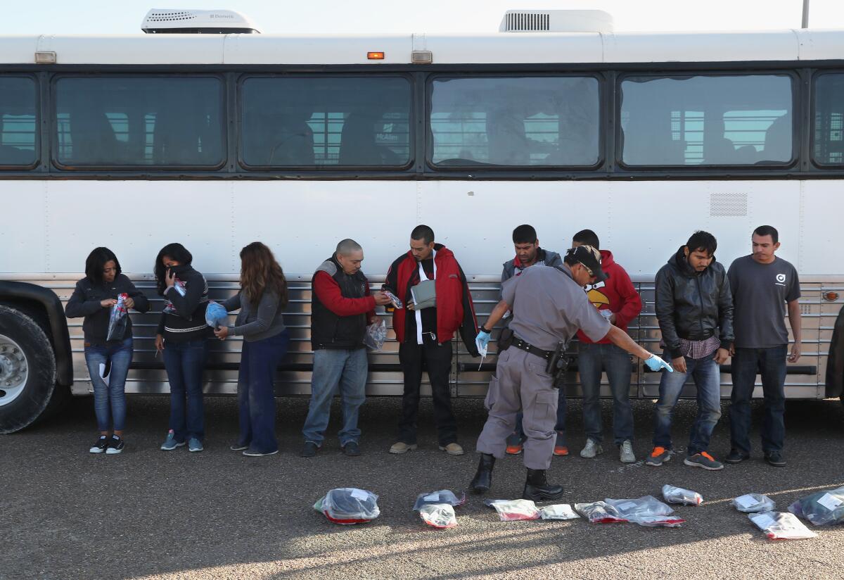Un grupo de personas recién deportadas, recogen sus pertenencias antes de ser conducidos a través de un puente internacional hacia México desde Hidalgo, Texas.