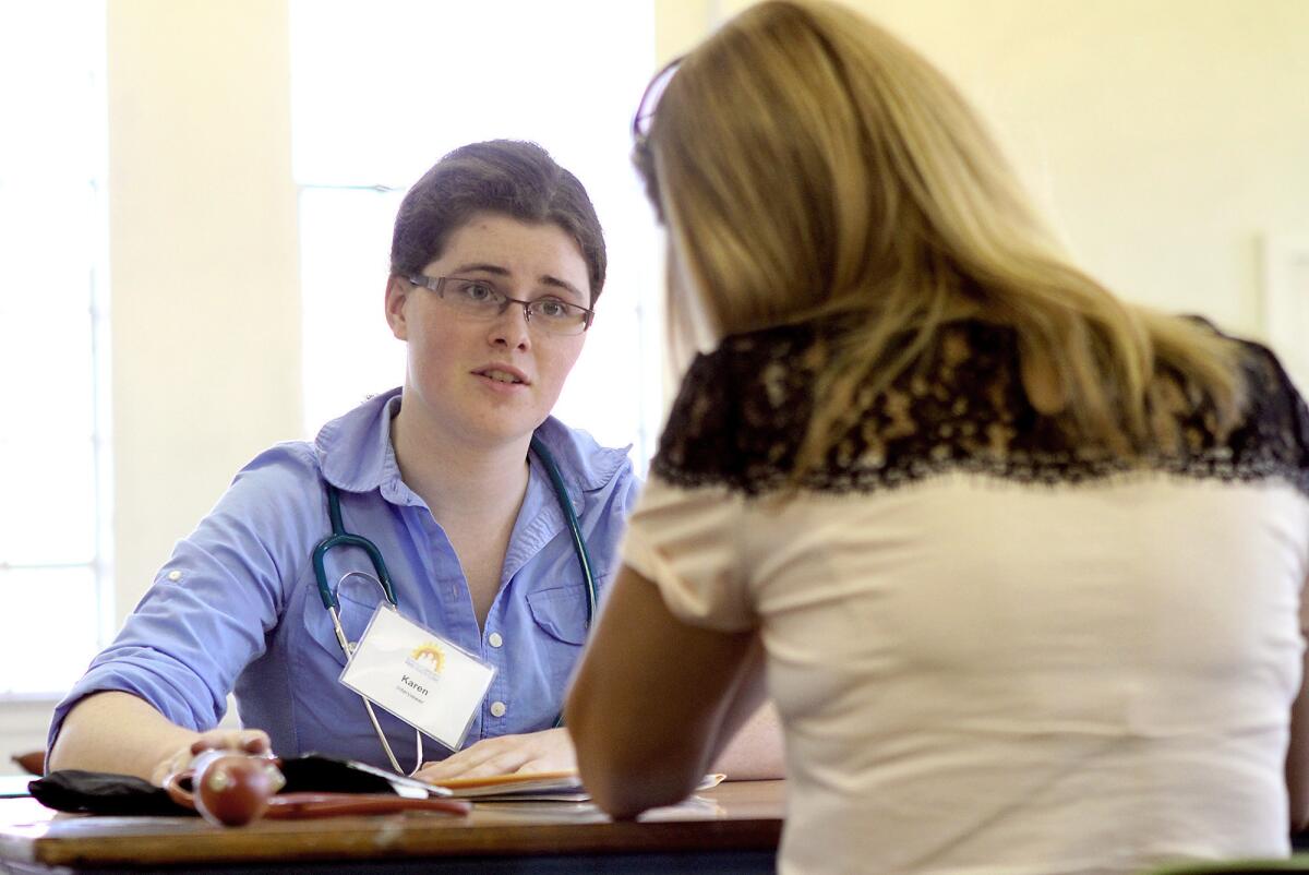 Interviewer Karen McCandliss talks to a patient the Glendale Free Health Clinic on Tuesday, Oct. 15, 2013.