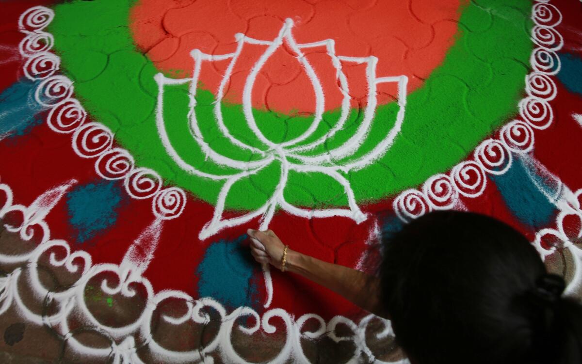 A supporter of India's ruling Bharatiya Janata Party (BJP) makes a floor design showing the party symbol Sunday as early results indicated the party leading in the Maharashtra state Assembly elections in Mumbai, India.