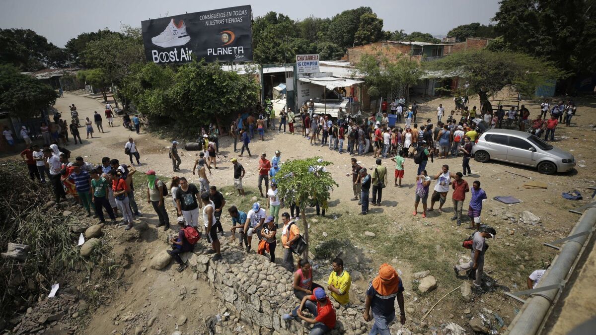 Venezuelan migrants wait for food being handed out by Colombian residents as others try to clear a roadblock created by Venezuelan security forces at the Simon Bolivar International Bridge near Cucuta, Colombia, on the border with Venezuela, on Sunday.
