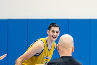 Aday Mara laughs while leaning leaning forward and looking toward coach Mick Cronin during practice.