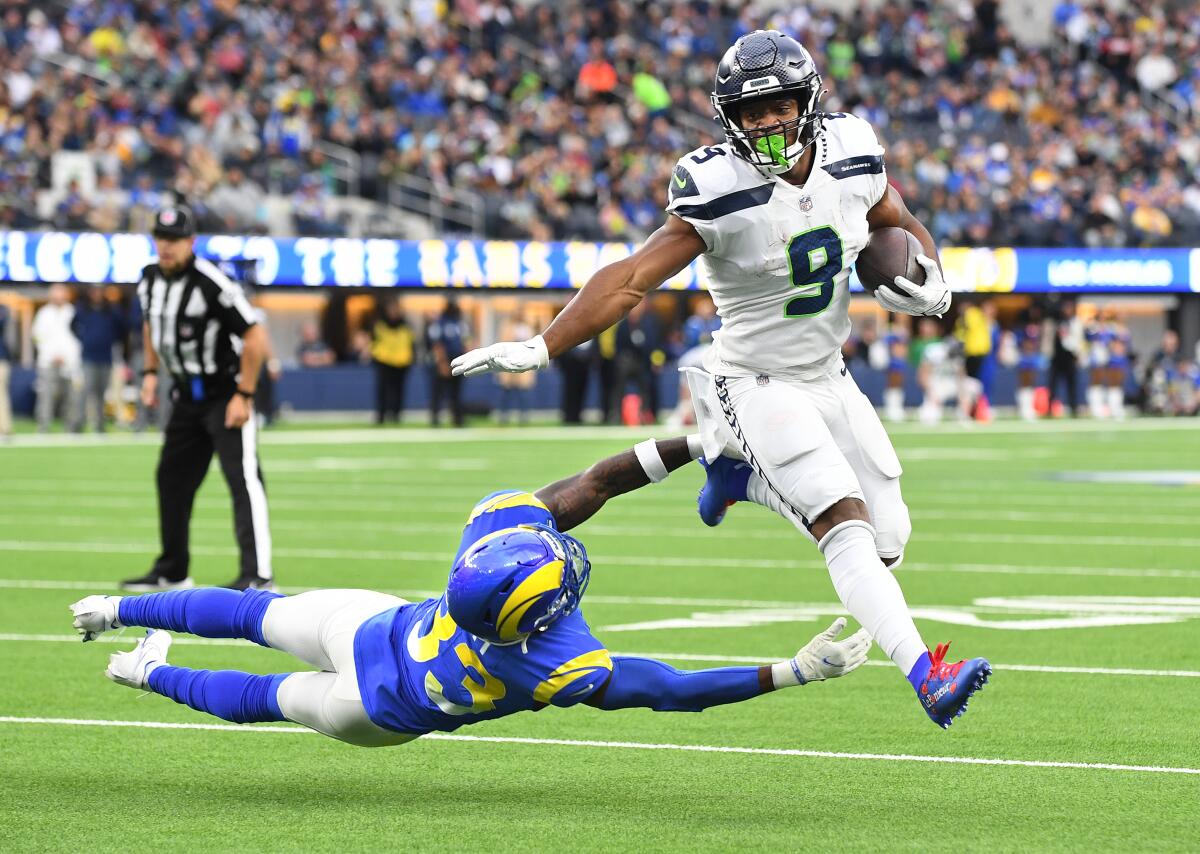 Seattle's Kenneth Walker runs past Rams defensive back Nick Scott in the first quarter.