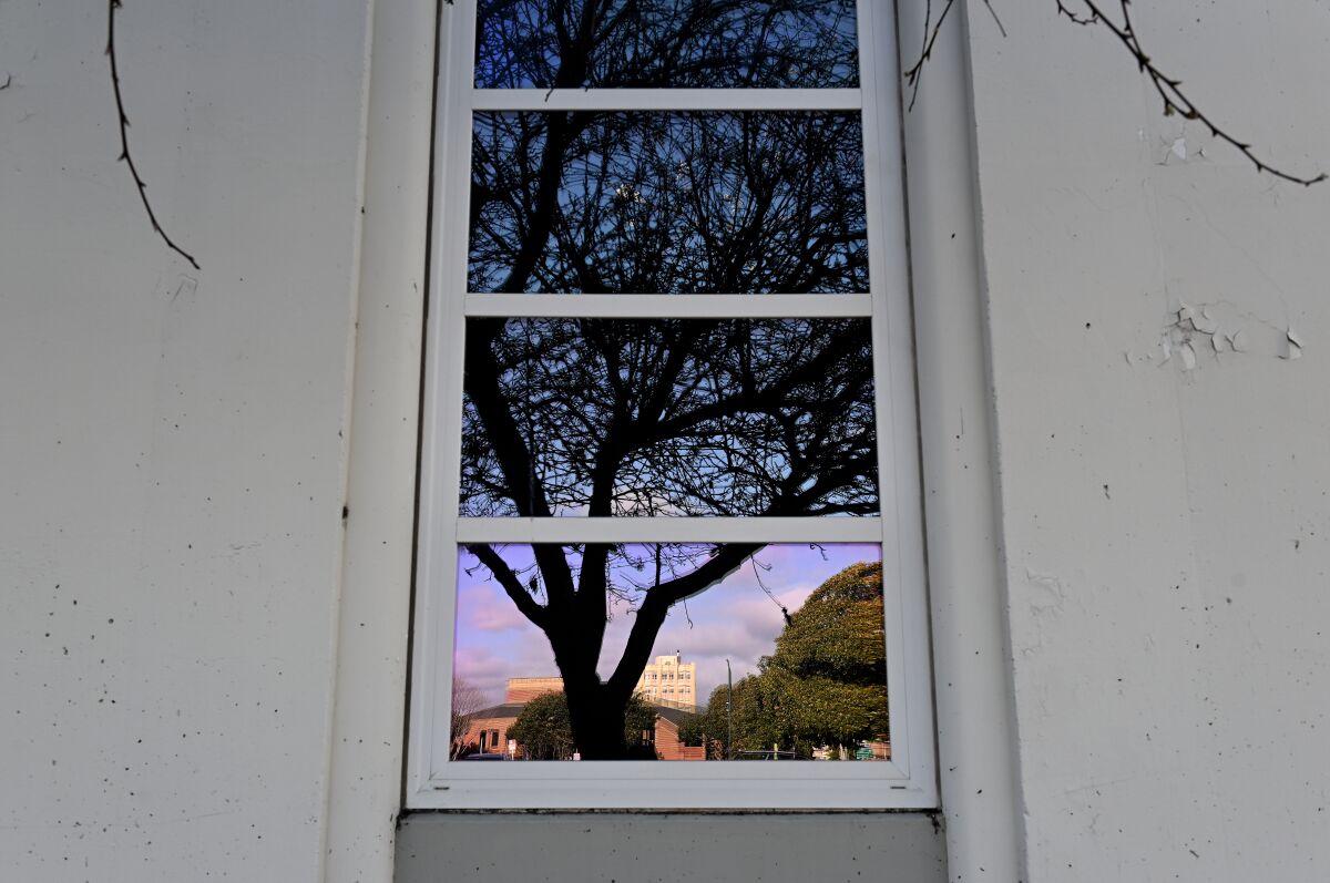 An office building is reflected in the window of the old Salinas Californian building.