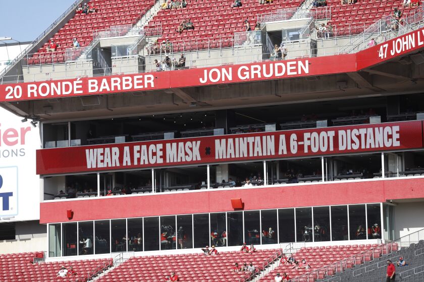 Signs that stress fans to wear a face mask are seen before an NFL football game in Tampa, Fla.