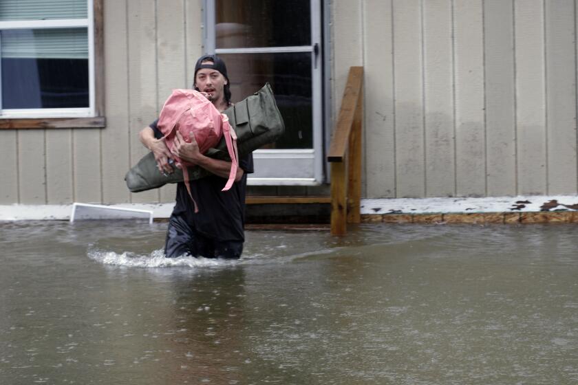 A man carries belongings through floodwaters from a home in Bridgewater, Vt., Monday, July 10, 2023. Heavy rain drenched part of the Northeast, washing out roads, forcing evacuations and halting some airline travel. (AP Photo/Hasan Jamali)