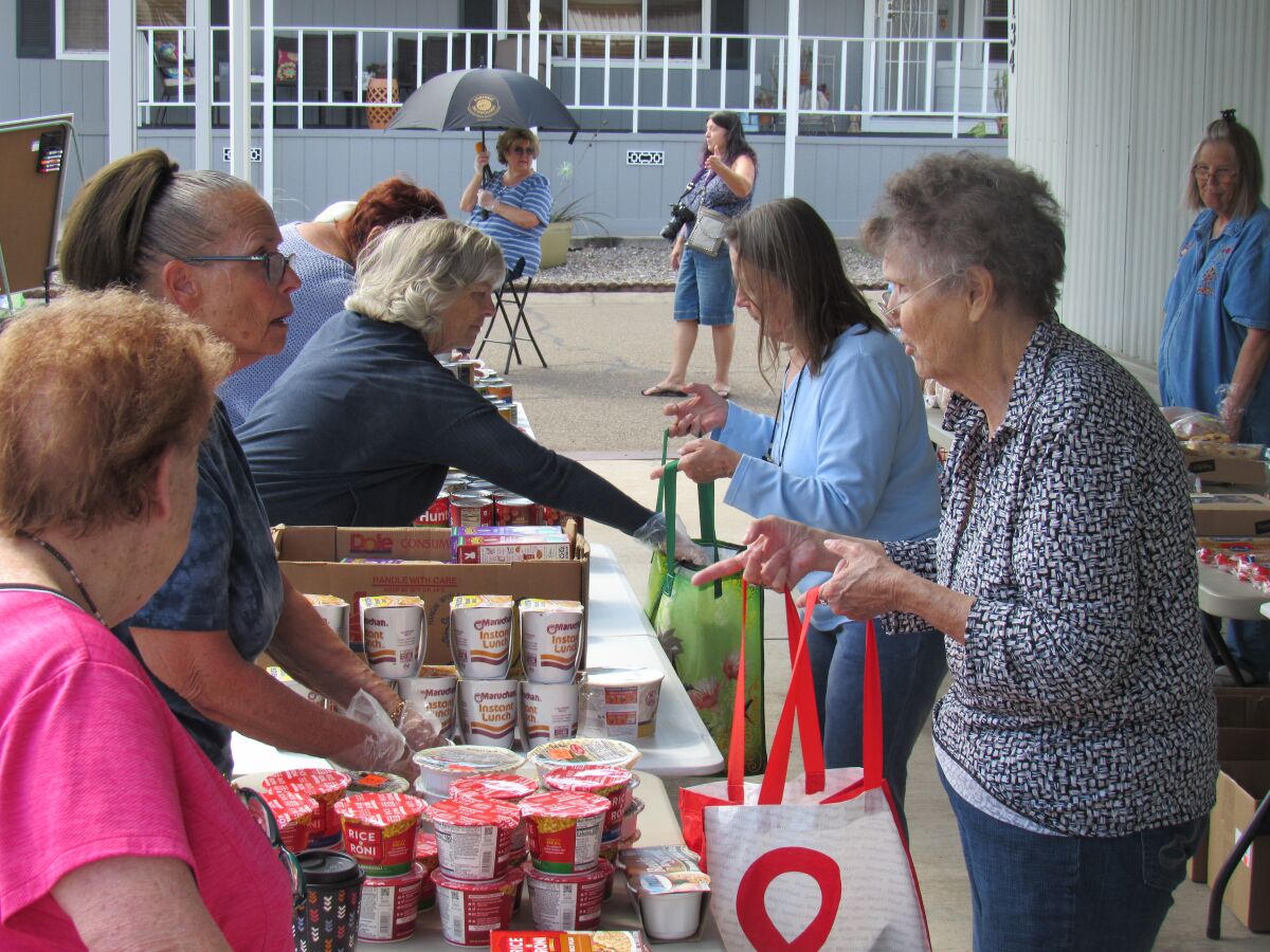 Senior shoppers at Meadowbrook Mobile Home Park in Santee fill their bags with food and other needs at a food sharing event held Sunday, March 29.