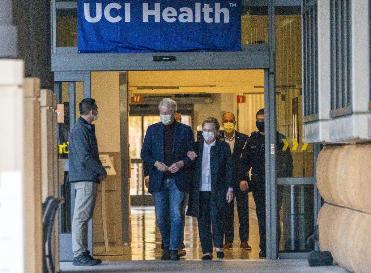 Former President Clinton and former Secretary of State Hillary Clinton walk out of the UC Irvine Medical Center.