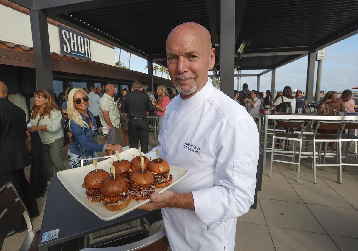 Chef Manfred Lassahn holds a plate of fish and chips sliders at Shor, a new concession stand at Huntington Beach.