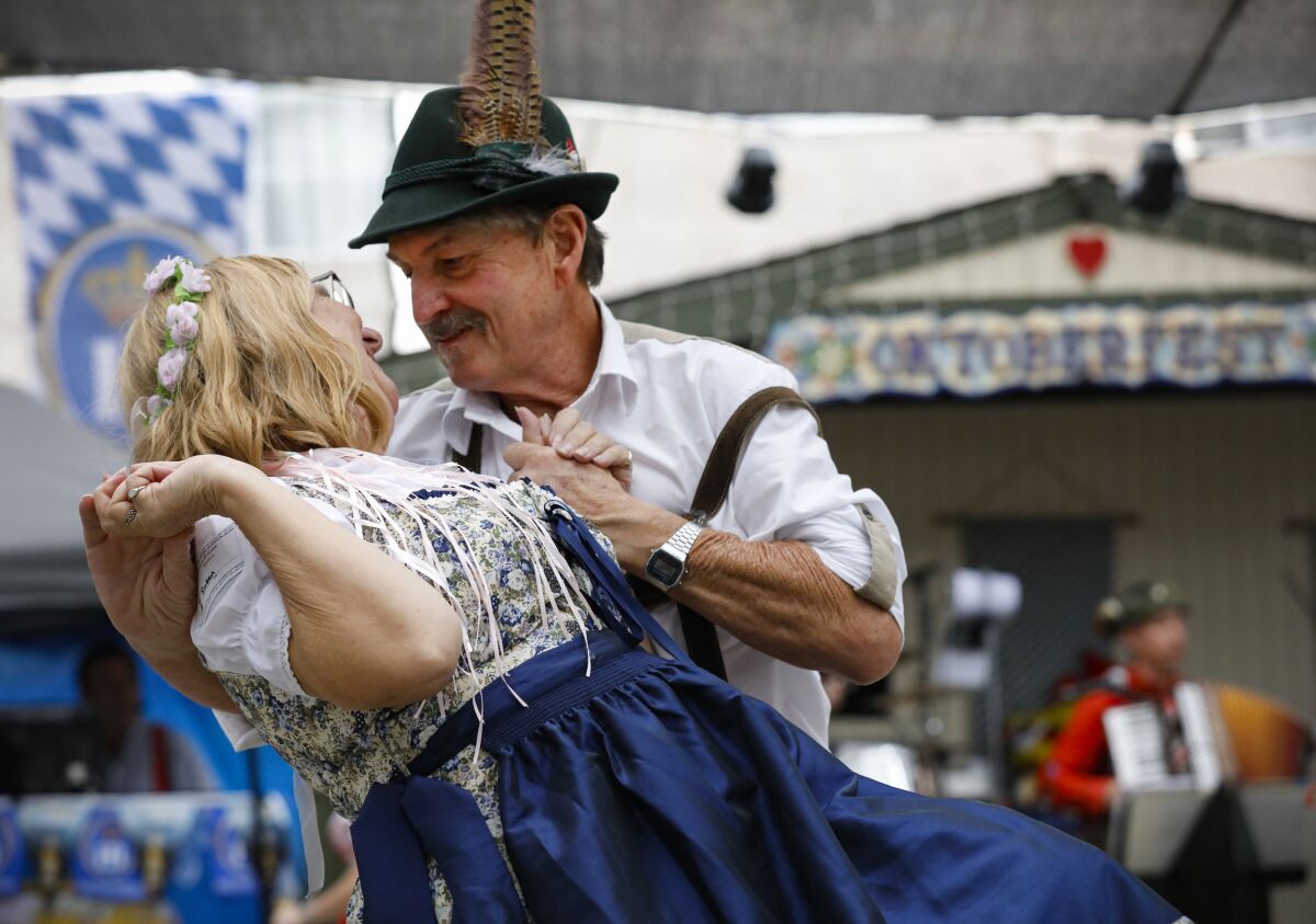 John Rollins (a la derecha) termina una danza folclórica alemana con su esposa, Susan, durante Oktoberfest 2021 en El Cajón.