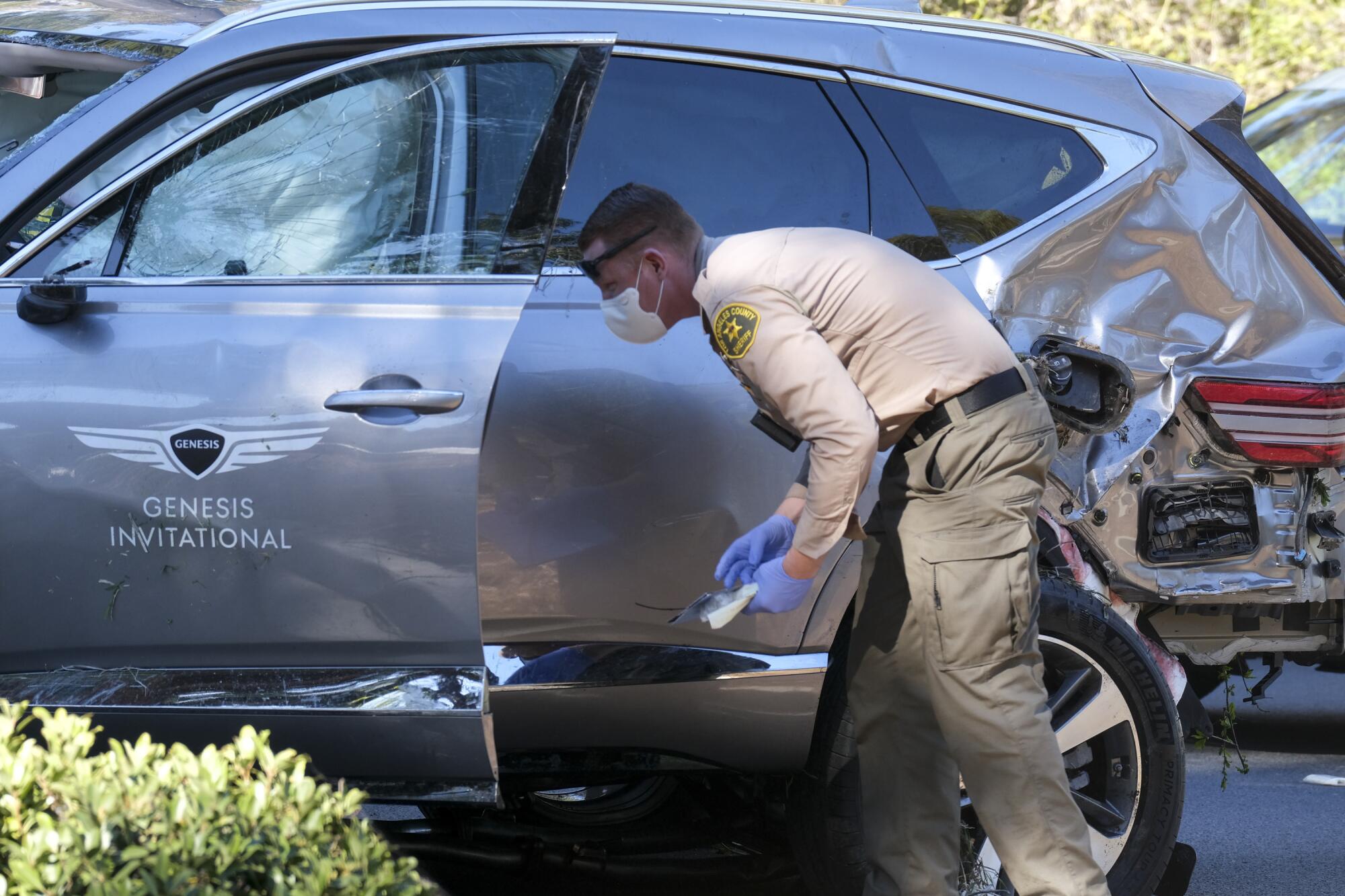 A law enforcement officer looks over the damaged vehicle. 