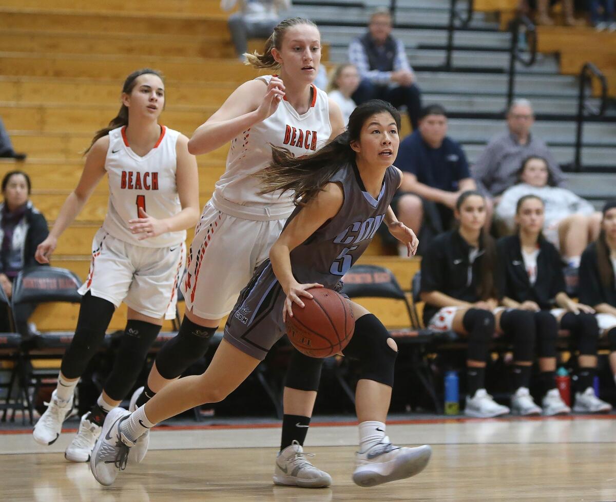 Corona del Mar's Samantha Uehara drives to the basket for a score around Huntington's Andie Payne in a Surf League road game on Jan. 17.