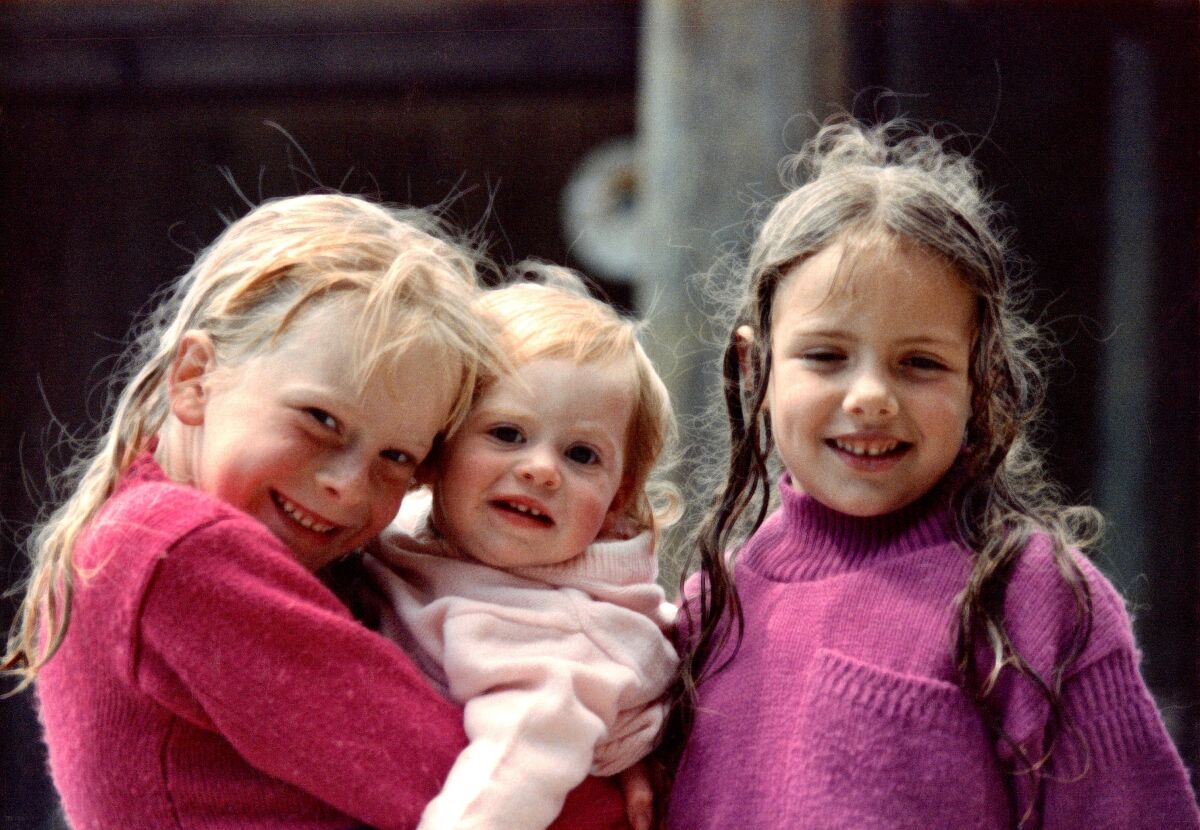 Three young sisters smile for a family photo