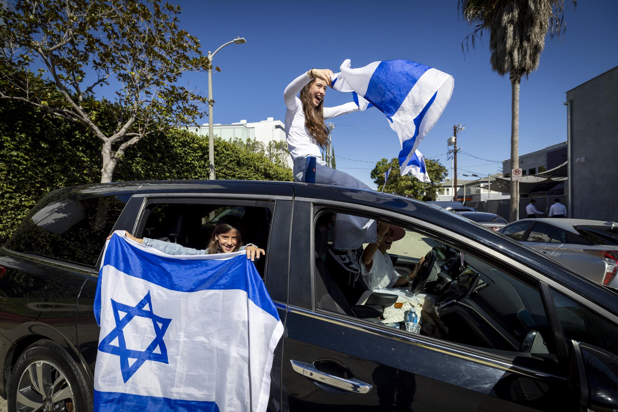 People display Israeli flags from their car while watching thousands marching to the Museum of Tolerance in Los Angeles.